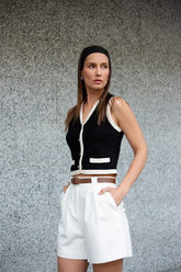 a lady in a black knit vest cardigan with white trim and a pair of white shorts